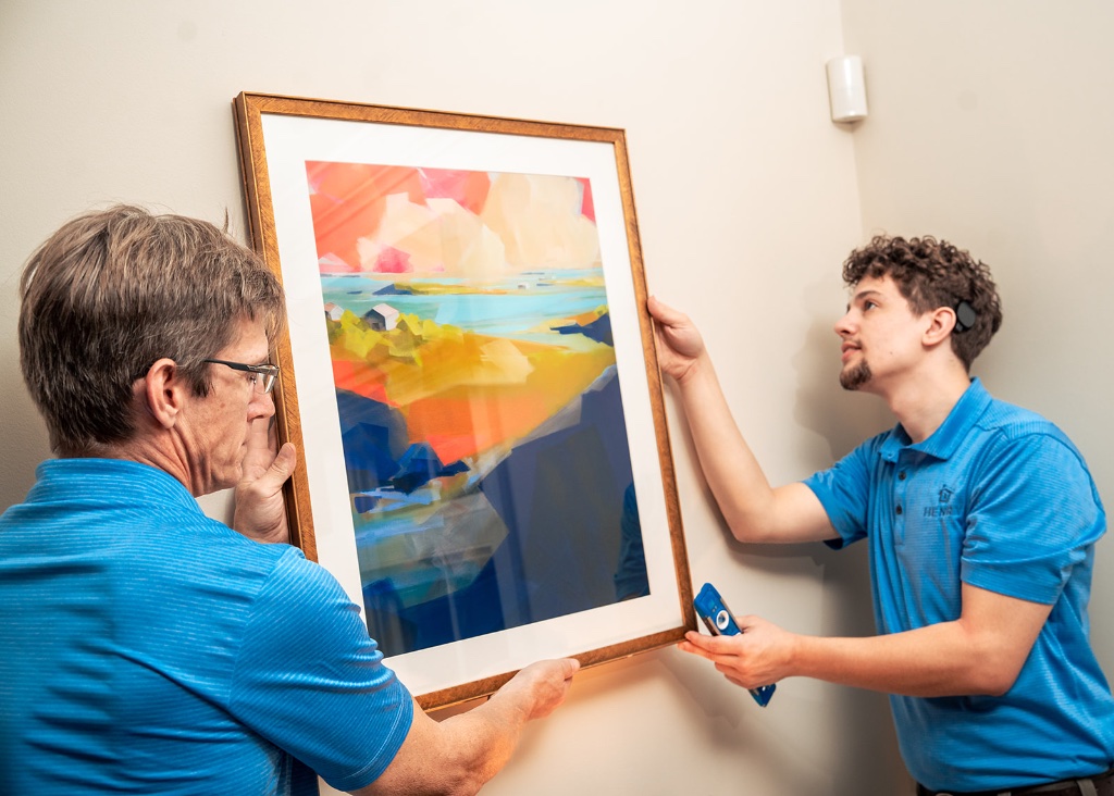 Henry Homes technician hanging artwork in a client's home